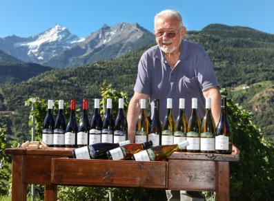 Der Besitzer von Maison Anselmet mit seinen Weinen und die Grivola im Hintergrund
